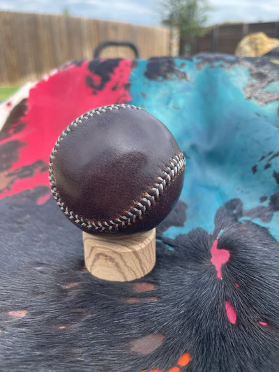 Brown leather baseball on wooden stand